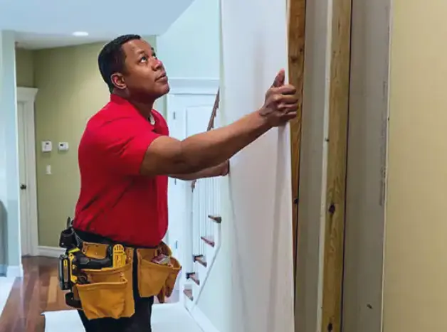 A male Mr. Handyman technician handing drywall in a customer's home.