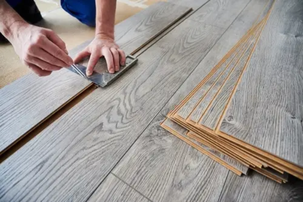 Worker installing laminate flooring planks using a click-lock method
