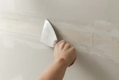 Applying the first coat of drywall mud over a seam using a putty knife