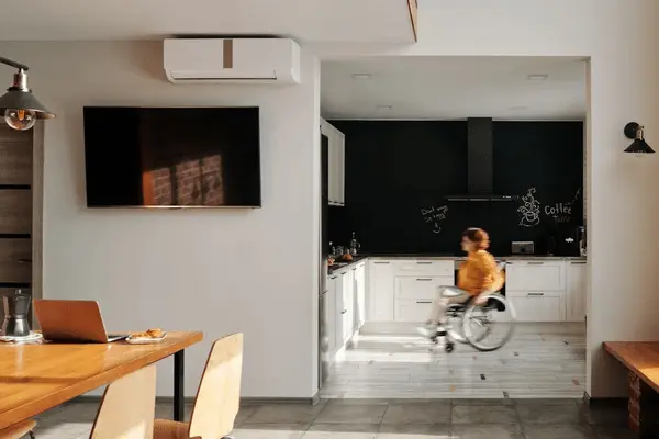 Woman in wheelchair moves in the kitchen of her house.