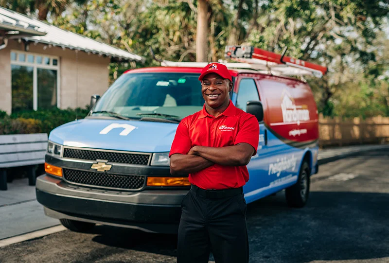 Mr. Handyman professional in uniform standing in front of a Mr. Handyman van.