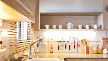 A completed kitchen remodel with open shelving below the upper cabinets, a white backsplash, and a magnetic knife rack.