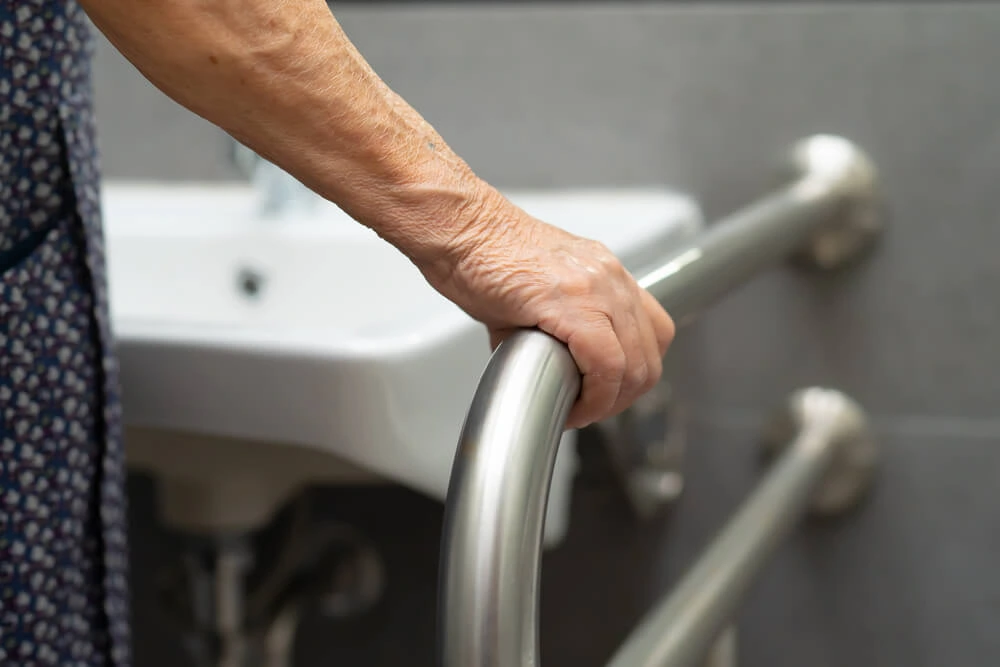 elderly person holding hand rail in bathroom