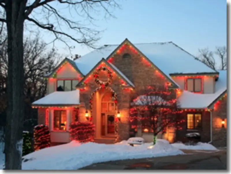 A house covered in christmas lights in the snow.