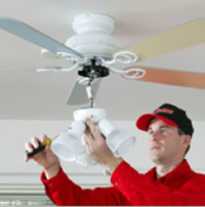 A man fixing a ceiling fan in a room.