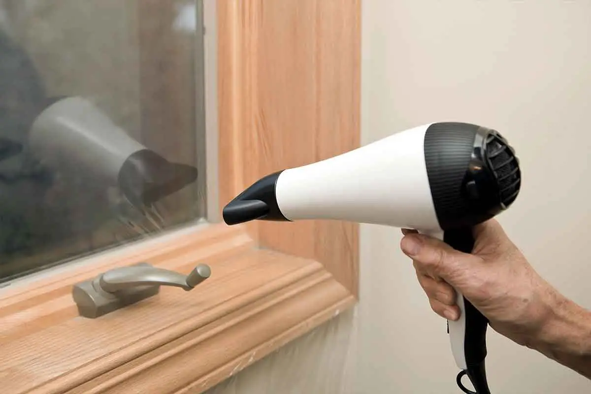 view of someone sealing insulation film on a window using a hair dryer