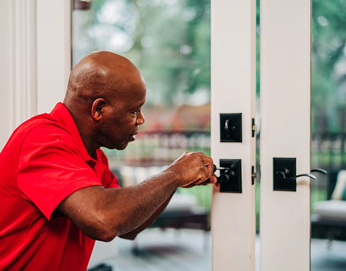 Mr. Handyman tech fixing a door handle during an exterior door installation.