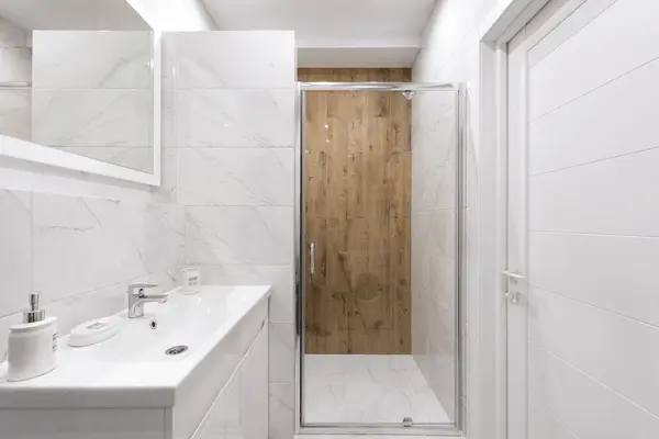 View of a white marble bathroom focused on a shower door