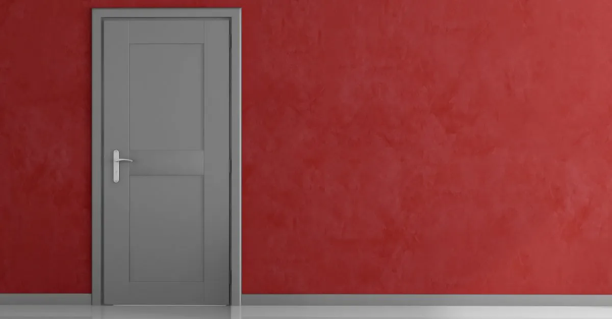 A closed, gray door installed on a red wall on the inside of a home in Tulsa, Oklahoma.