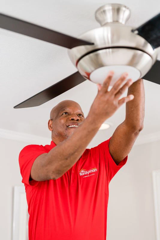 Mr. Handyman technician completing a ceiling fan installation in a home.
