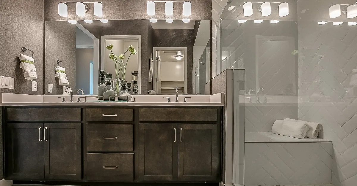 A newly completed bathroom remodel with new cabinets and a glass shower enclosure with a built-in bench.