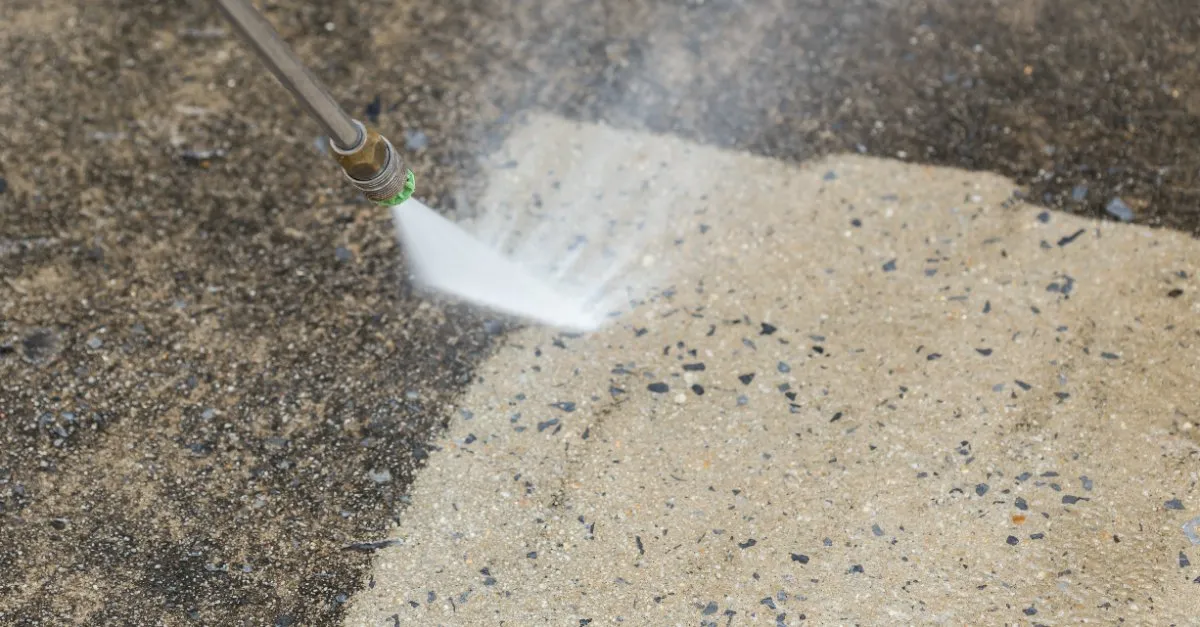 A stone surface with a layer of built-up grime being cleaned away by a jet of water during an appointment for pressure washing in Keller, TX.