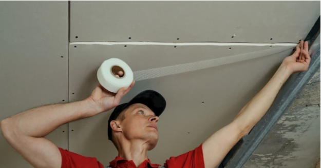 A person using a tape to adhesive the ceiling.